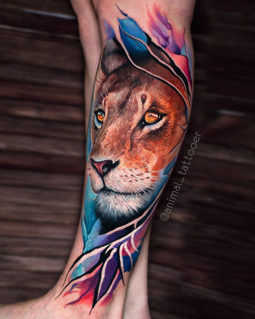 Colorful lion tattoo on a person's forearm with vibrant blue, pink, and purple accents, showcasing animal art.