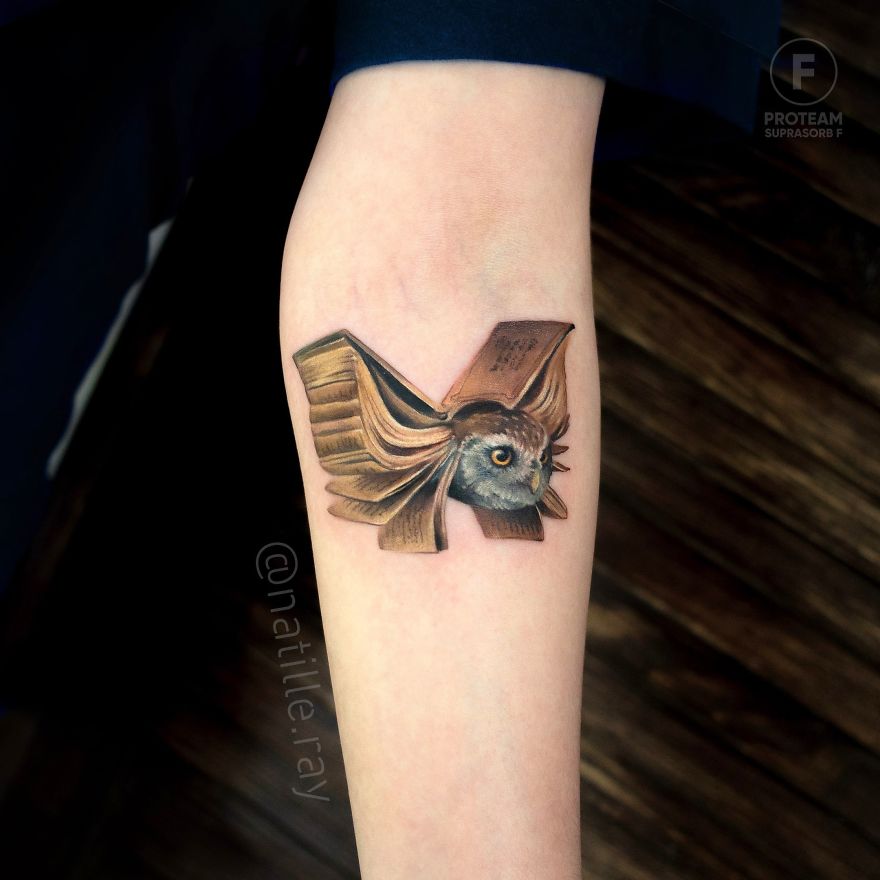 Colorful and bright animal tattoo of an owl with detailed wings on an arm.