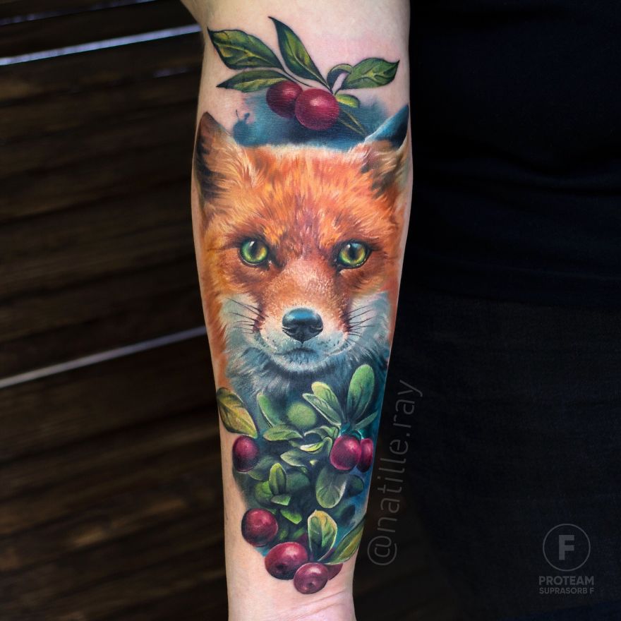 Colorful animal tattoo of a fox with berries and leaves on an arm.