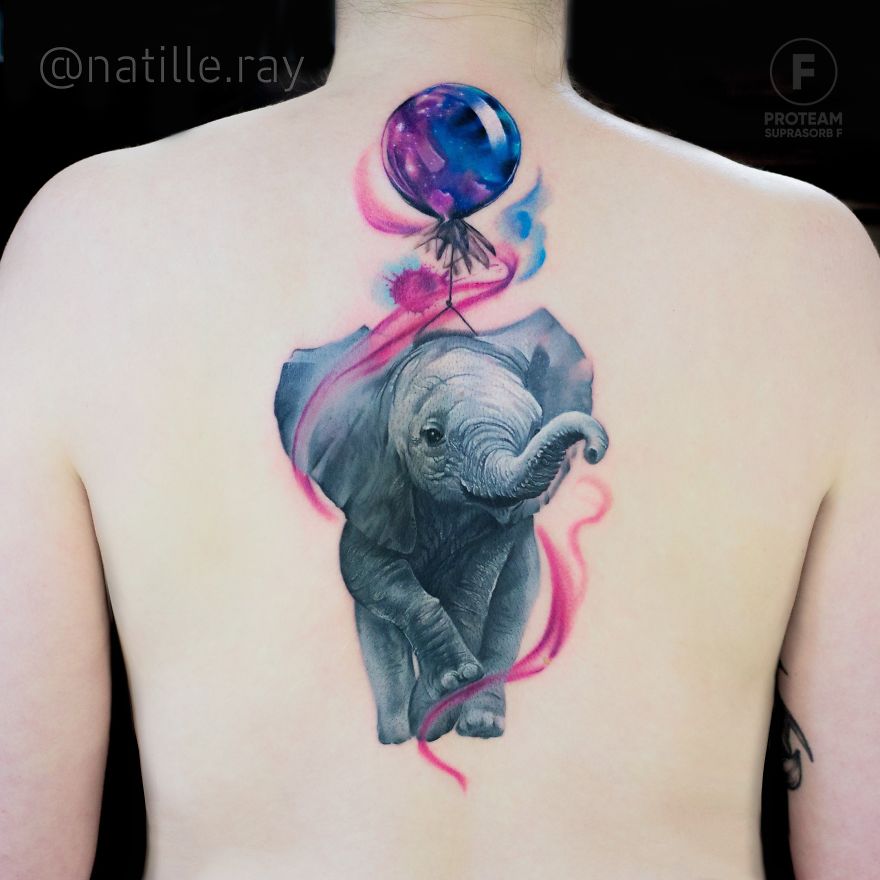 Colorful elephant tattoo with a galaxy balloon on back, showcasing vibrant animal art.
