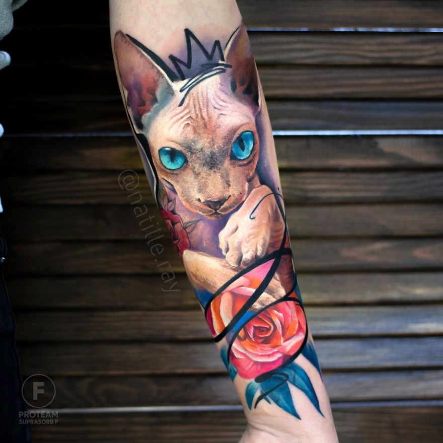 Colorful and bright animal tattoo of a cat with blue eyes and a rose on an arm.