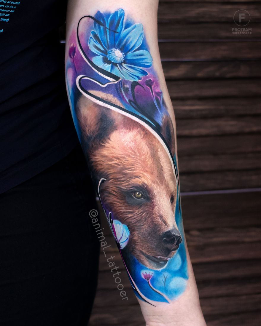Colorful animal tattoo featuring a bear and flowers on a person's arm.
