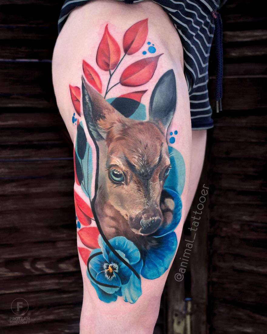 Colorful animal tattoo of a doe with vibrant red leaves and blue flowers on a leg.