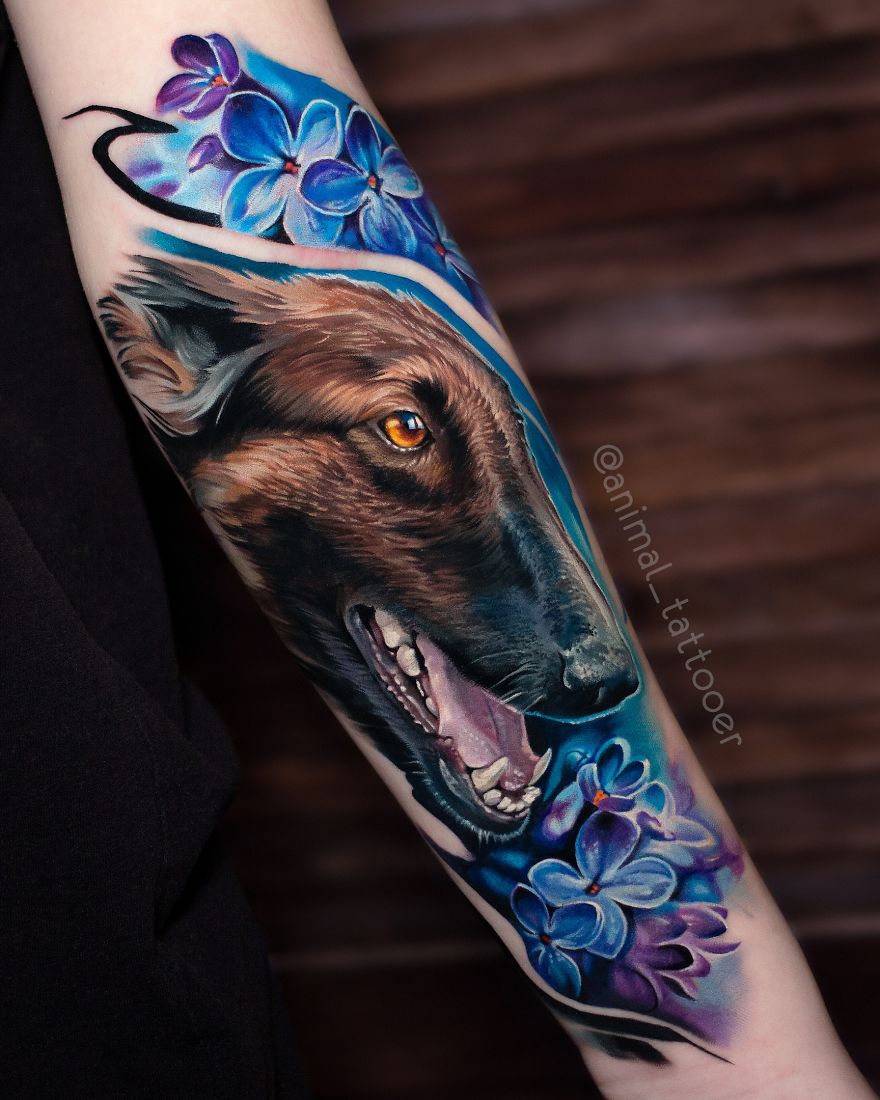Colorful and bright animal tattoo of a dog's head with vibrant purple flowers on a person's forearm.