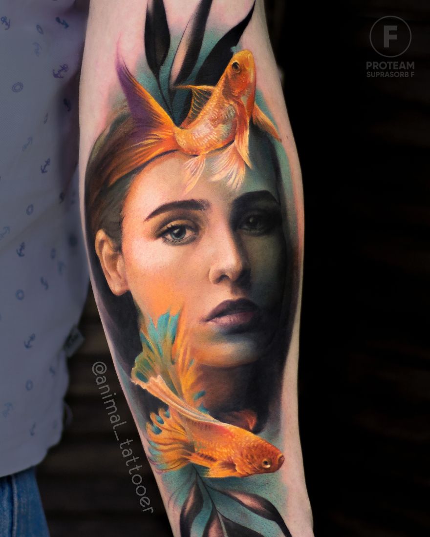 Colorful animal tattoo featuring a woman's face with vibrant fish on a person's arm.