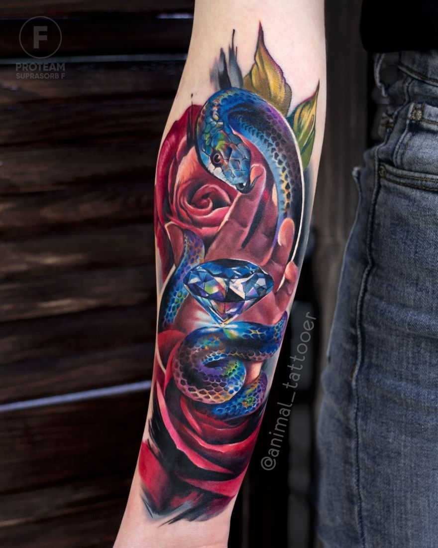 Colorful animal tattoo of a snake wrapped around a rose with a diamond on forearm.
