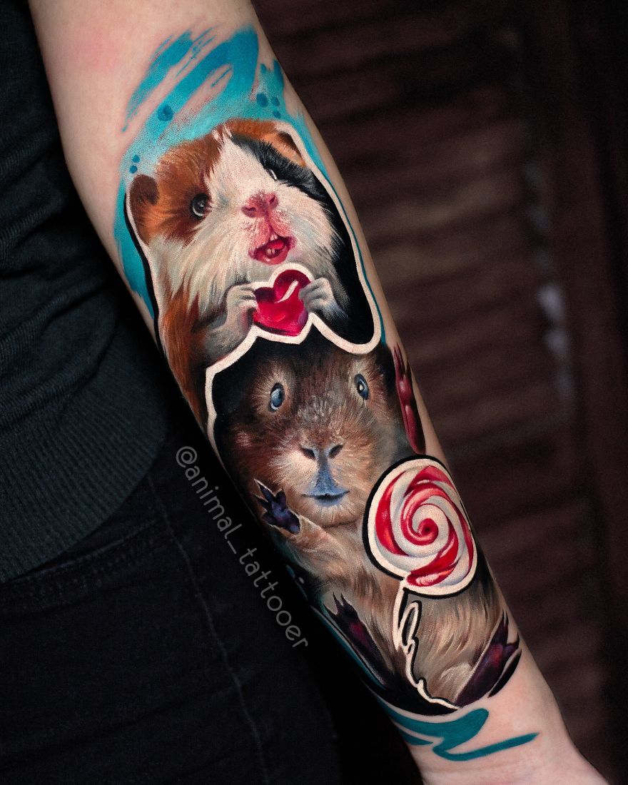 Colorful and bright animal tattoos of two guinea pigs holding a heart and a lollipop on a person's forearm.