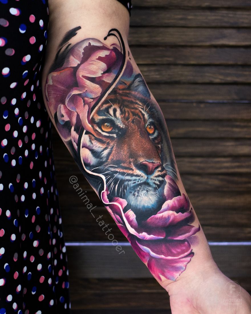 A colorful and bright tiger tattoo with floral elements on a person's forearm.