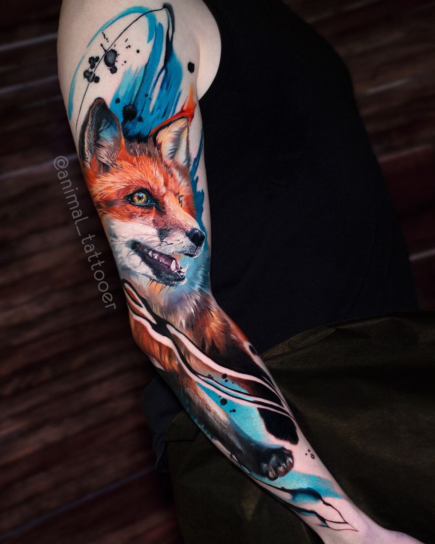 Colorful and bright animal tattoo of a fox on a person's arm with artistic blue and orange elements.
