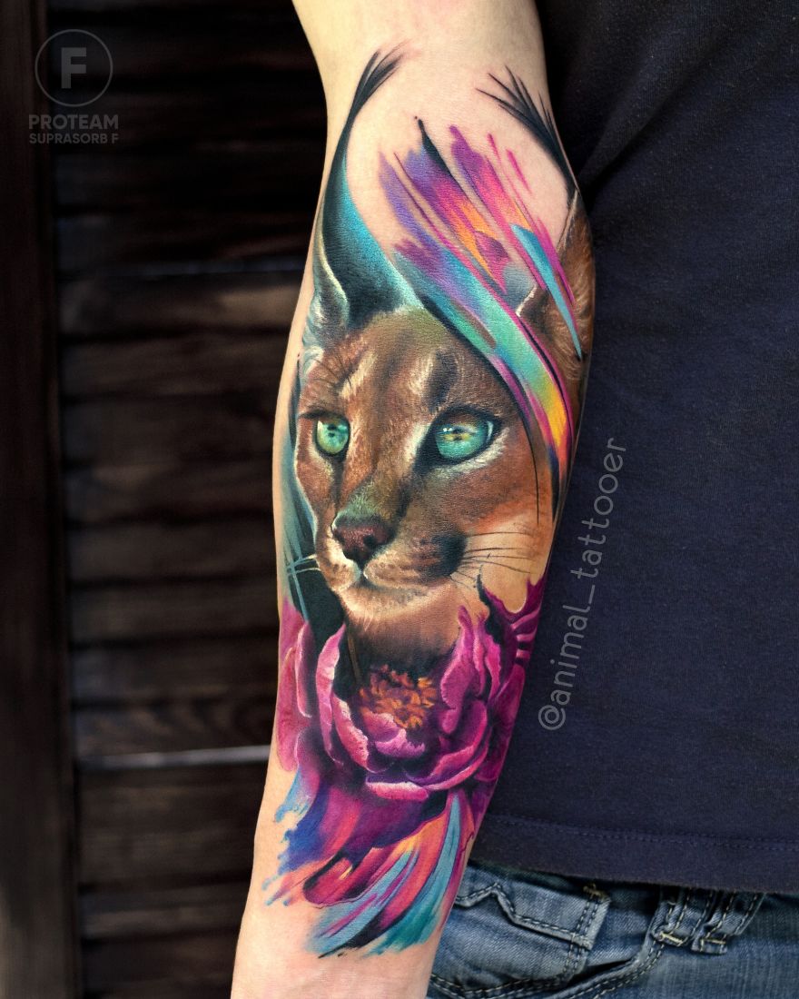 Colorful and bright animal tattoo of a caracal surrounded by vibrant flowers on a person's arm.