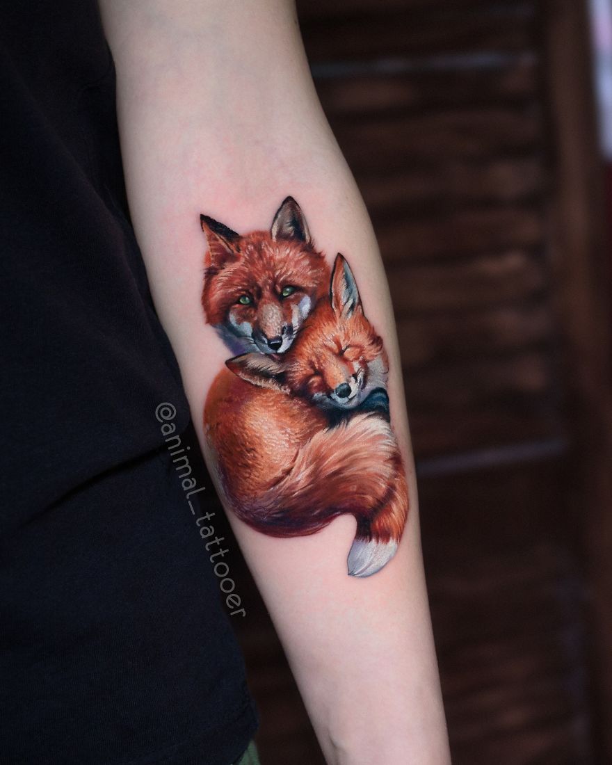 Colorful tattoo of two foxes on an arm, showcasing bright animal art.
