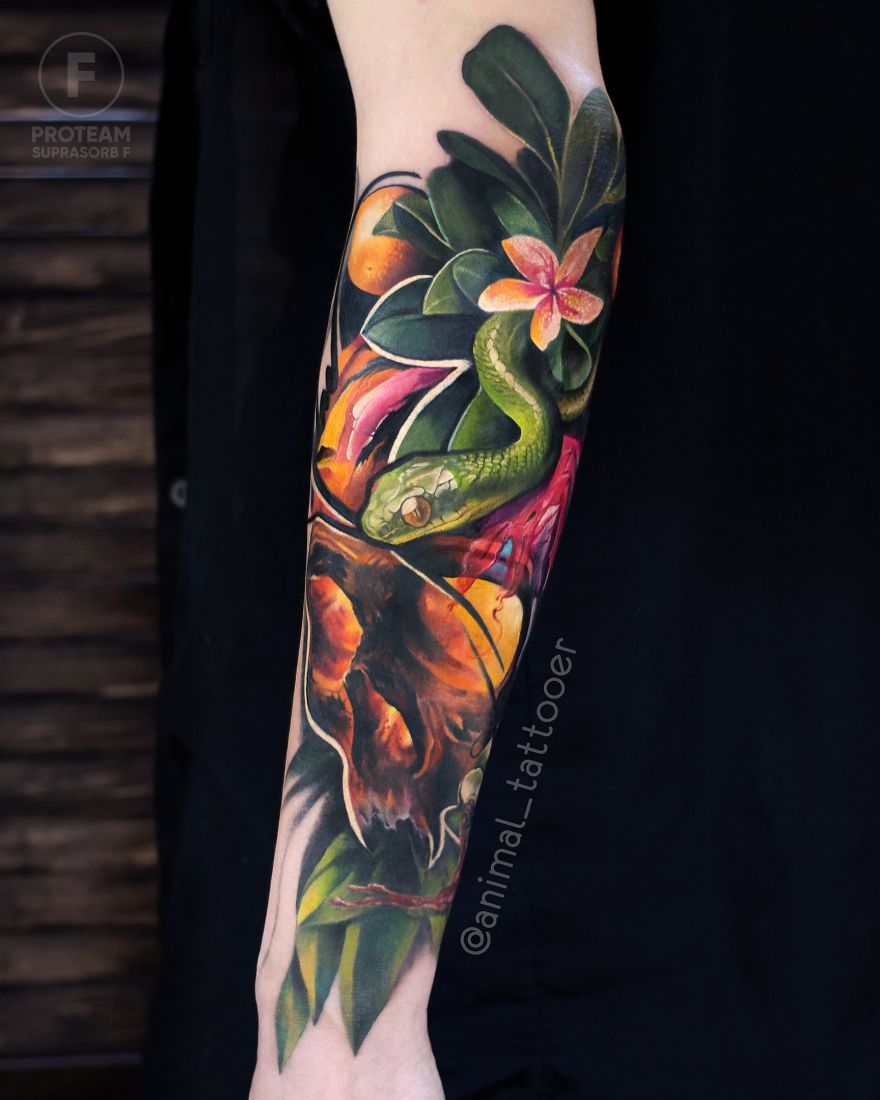 Colorful and bright animal tattoo featuring a green snake and tropical flowers on a forearm.