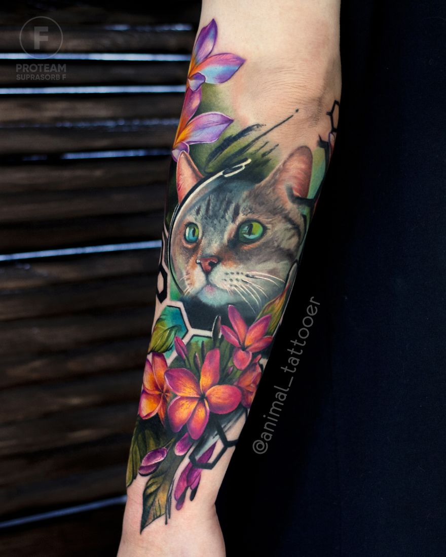Colorful animal tattoo featuring a cat with vibrant flowers on a person's forearm.