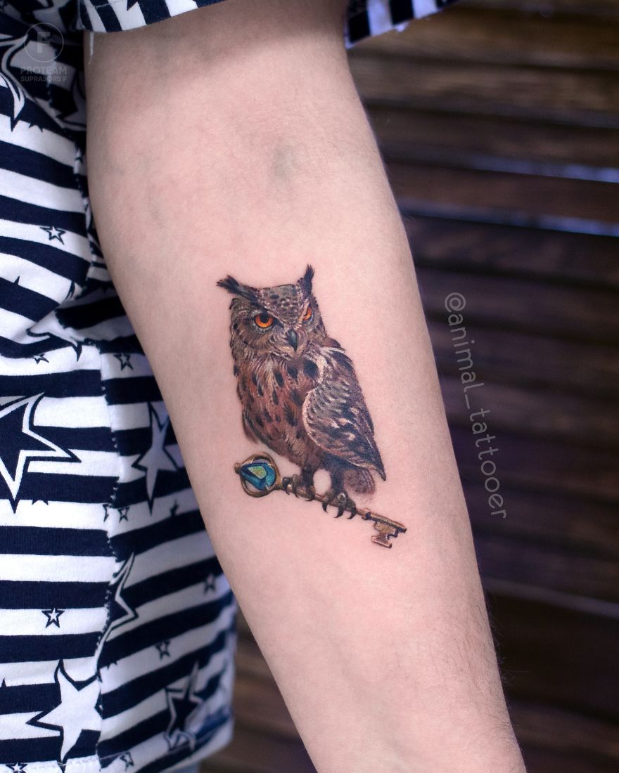 Colorful owl tattoo on a person's forearm, featuring detailed artwork in a vibrant design.