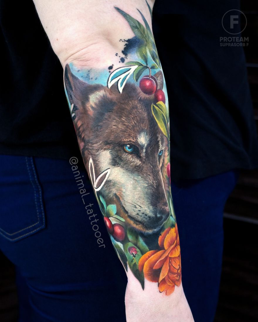 Colorful animal tattoo of a wolf on a person's forearm, featuring vibrant flowers and cherries.