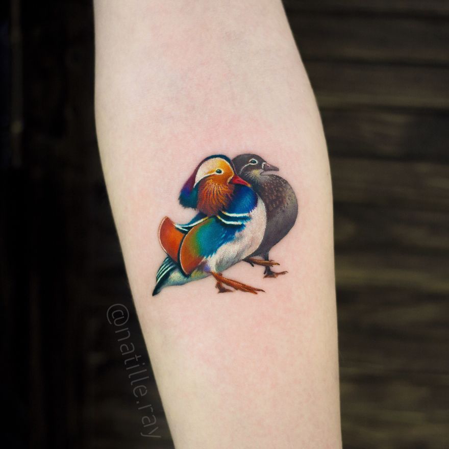 Colorful and bright animal tattoo of two ducks on forearm, showcasing vibrant artistry.