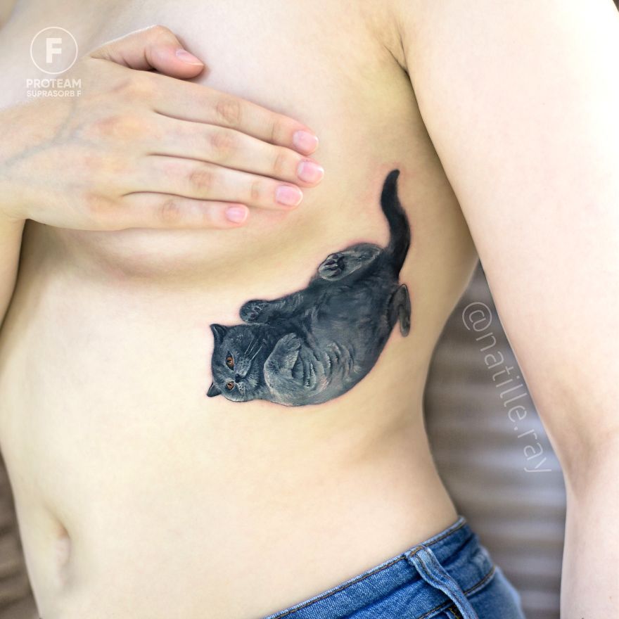 Person with a colorful cat tattoo on their side, showcasing bright and detailed animal artwork.