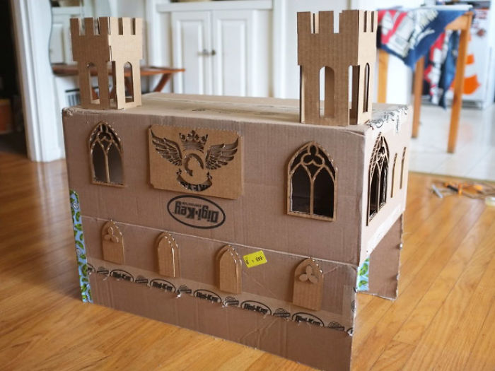 Cardboard fort built for a cat with castle-like towers and windows as an ecological solution for box reuse.