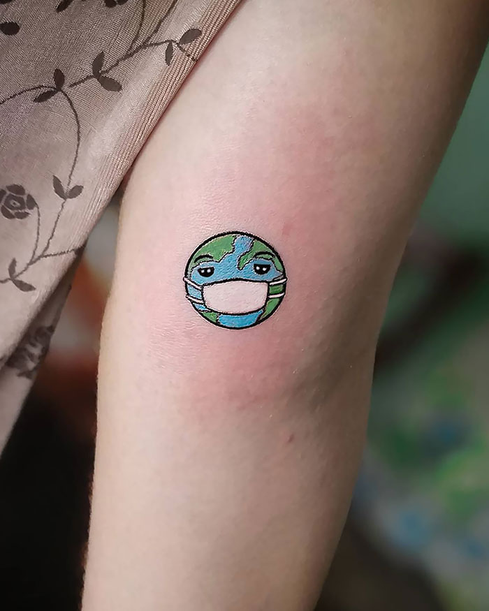 Creative Covid-19 tattoo of a globe wearing a mask on an arm.