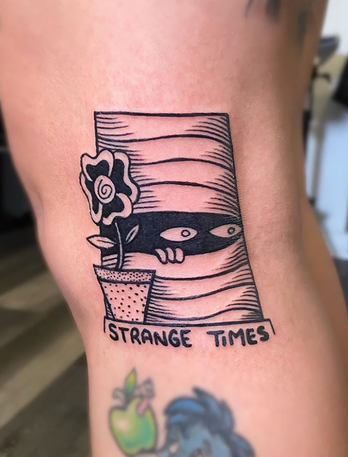 Creative Covid-19 tattoo featuring a peeking figure behind blinds labeled "Strange Times" with a flower pot.