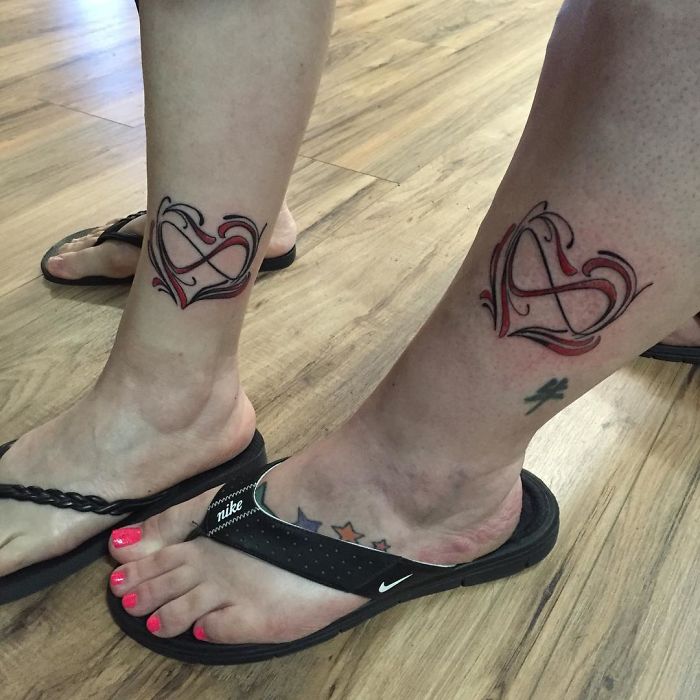 Heart infinity tattoo designs on legs, frequently requested by clients, showcased on a wooden floor.