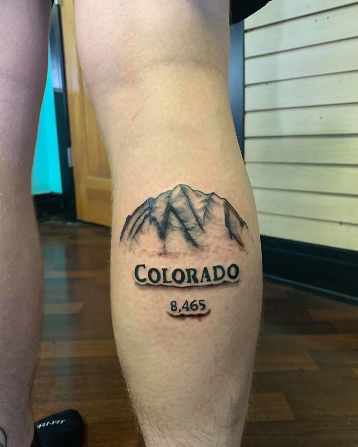 Leg tattoo of a mountain range with the word "Colorado" and the number 8,465, showcasing commonly requested tattoo designs.