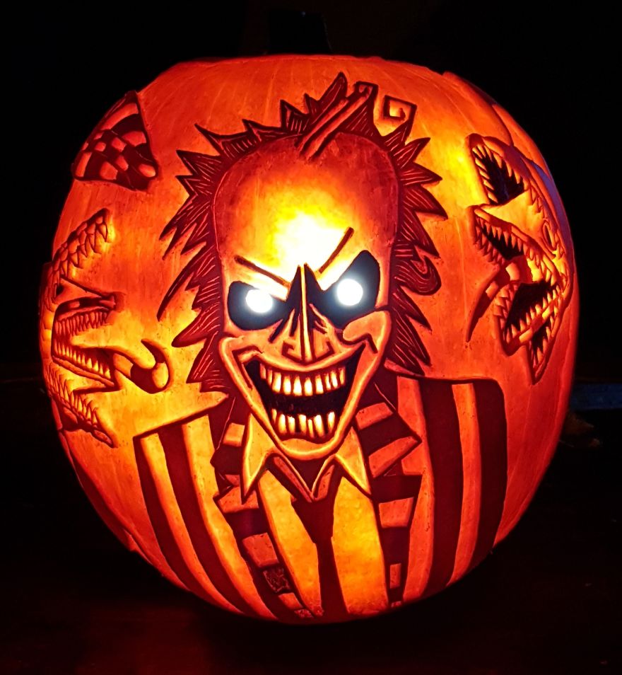 Pumpkin carving depicting a horror scene character with glowing eyes and sharp teeth, featuring intricate details.