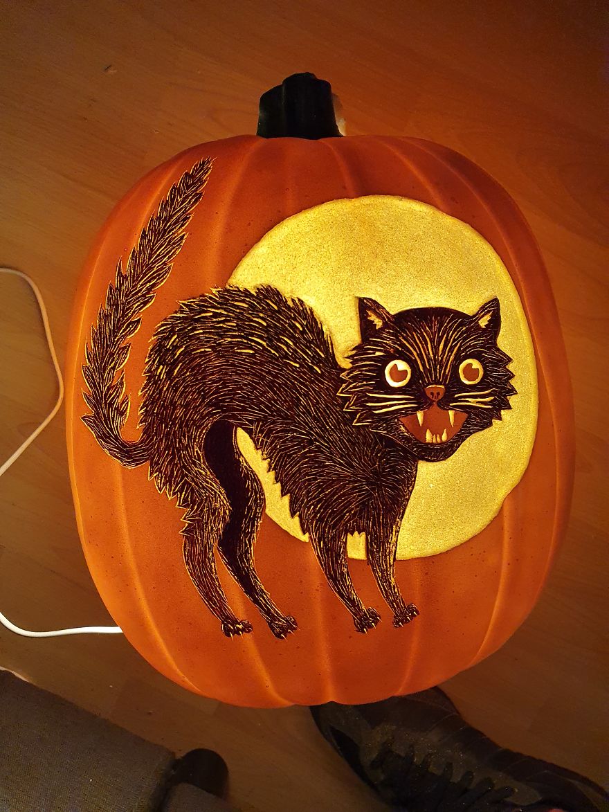 Pumpkin carving of a spooky black cat in front of a glowing moon, resembling a horror scene character.