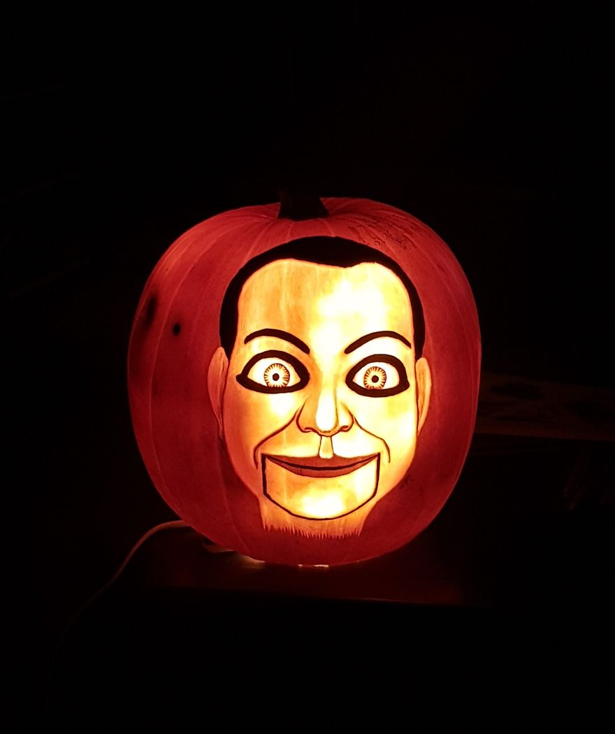 Pumpkin carving resembling a horror scene character with glowing eyes and a sinister smile.