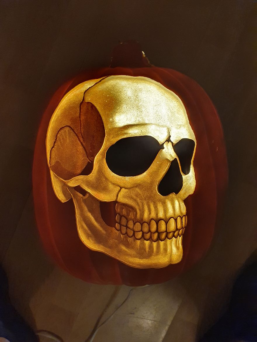 Pumpkin carving resembling a skull, inspired by horror scene characters, with detailed shading and glowing features.