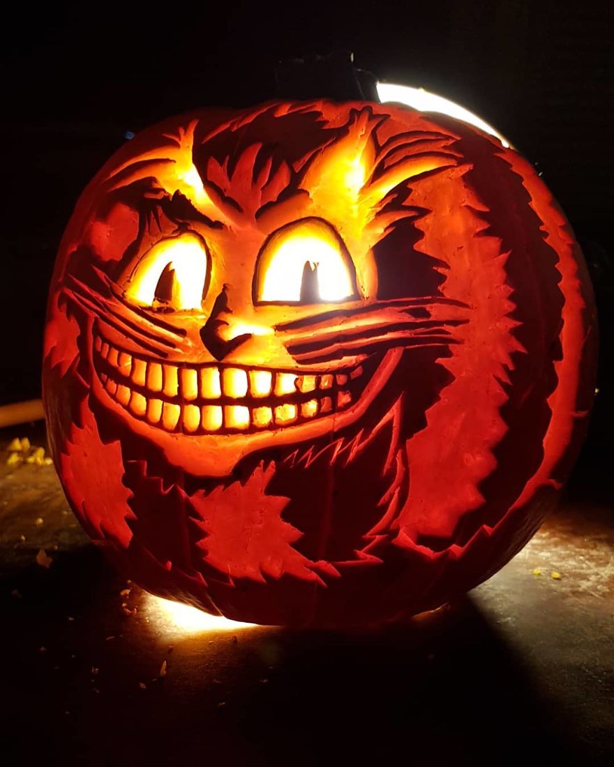 Pumpkin carving resembling a horror scene character with a wide grinning face illuminated from within.