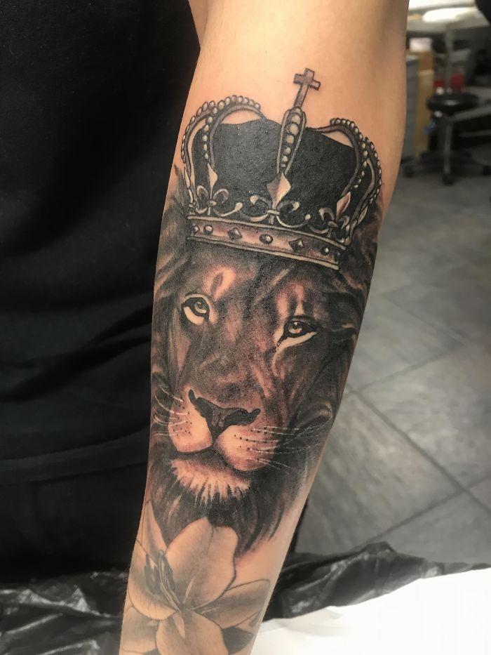 Tattoo of a lion with a crown on forearm, common design tattoo artists are tired of.