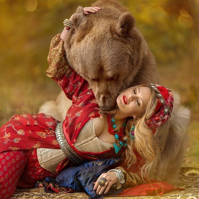Russian Brown Bear and woman in traditional attire posing outdoors during a modeling photoshoot with autumn background.