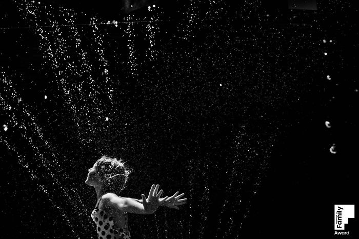 Child enjoying water splash in a candid family moment, showcasing the art of capturing a family moment in photography.