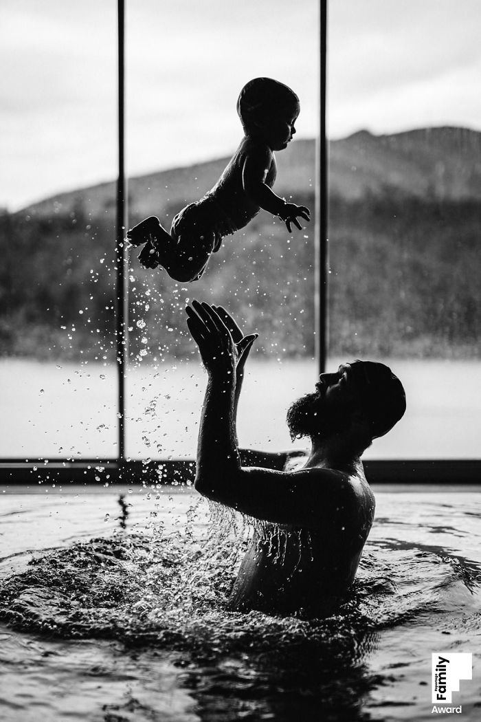 Father playing with baby in water, capturing a beautiful family moment with water splashing and joyful interaction.