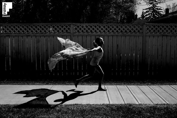 Child running with scarf outdoors, showcasing the art of capturing a family moment in an award-winning black and white photo.