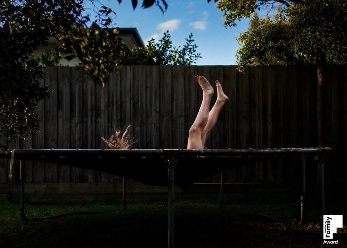 Child bouncing high on trampoline in backyard, capturing a joyful family moment with natural lighting and vibrant colors.
