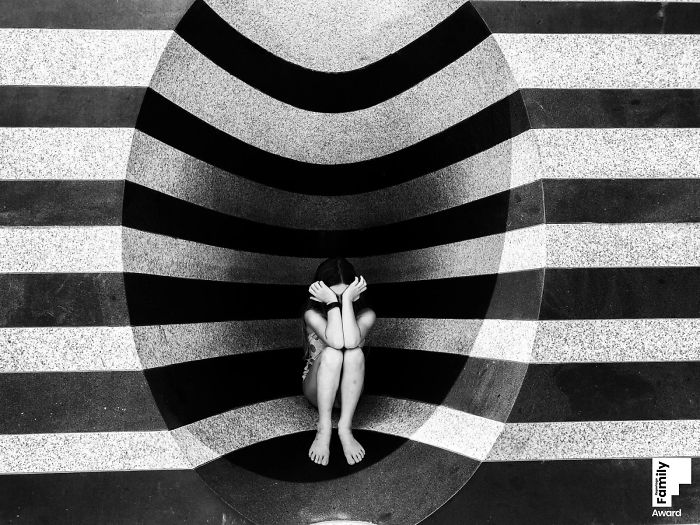 Child sitting with head in hands in striped black and white setting, showcasing the art of capturing a family moment.