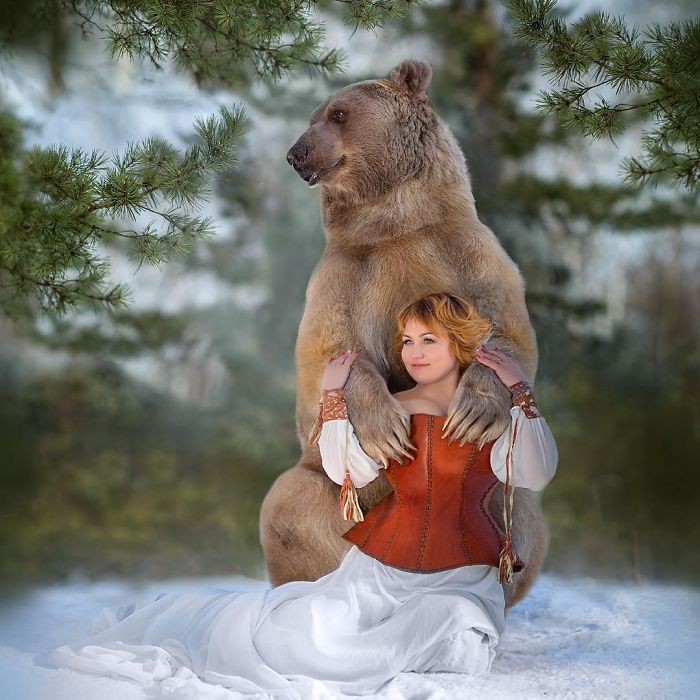 Russian brown bear raised by humans posing with woman in winter setting, starting a unique modeling career.
