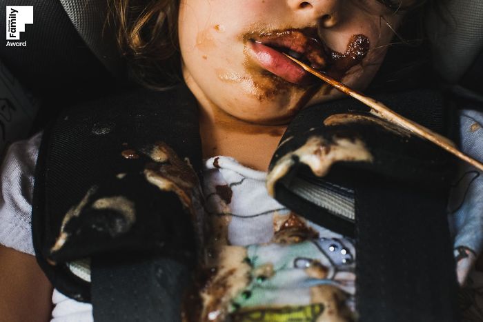 Close-up of a child with messy chocolate on face and clothes, capturing a candid family moment award-winning photo.