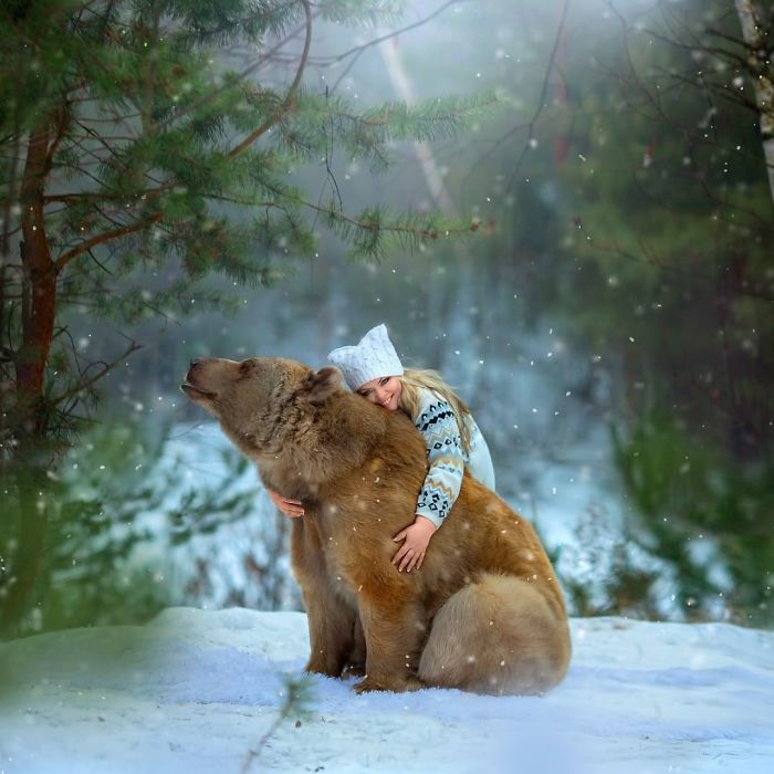 Young woman hugging a Russian brown bear in snowy forest, showcasing the bear’s modeling career and human bond.