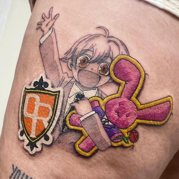 Tattoo of anime character with pink bunny patch design, resembling sewn-on patches.