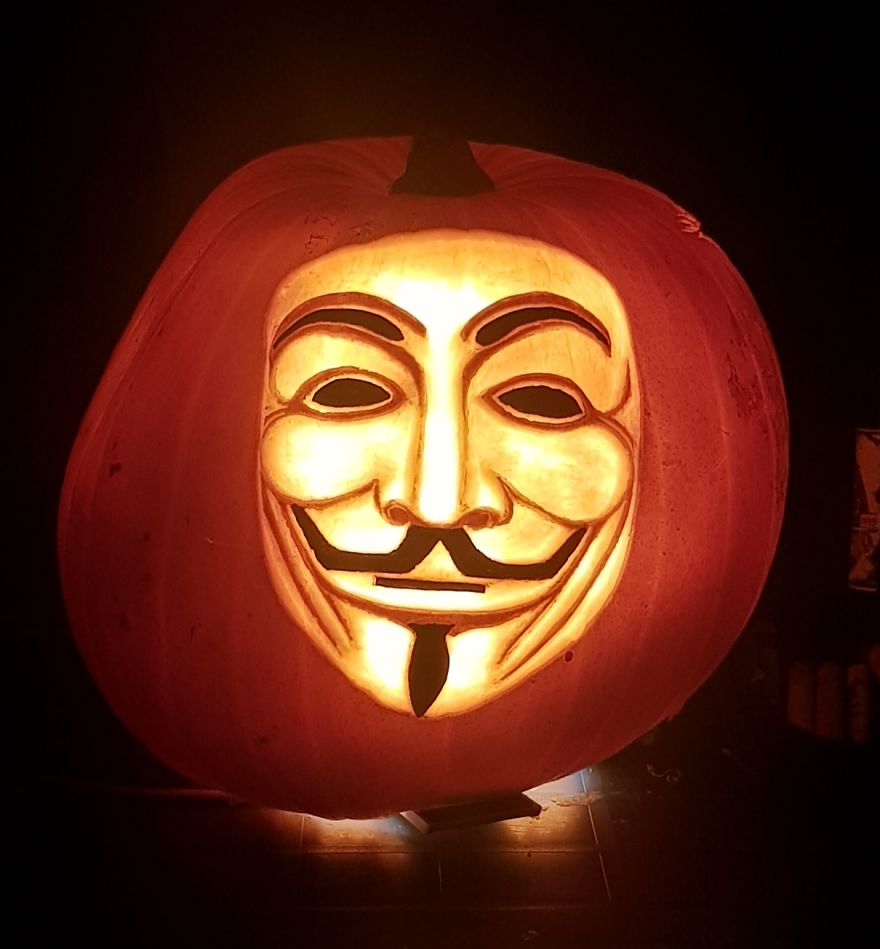 Carved pumpkin with a glowing Guy Fawkes face, showcasing badass pumpkin carving skills. Carved pumpkin with a glowing Guy Fawkes face, showcasing badass pumpkin carving skills.