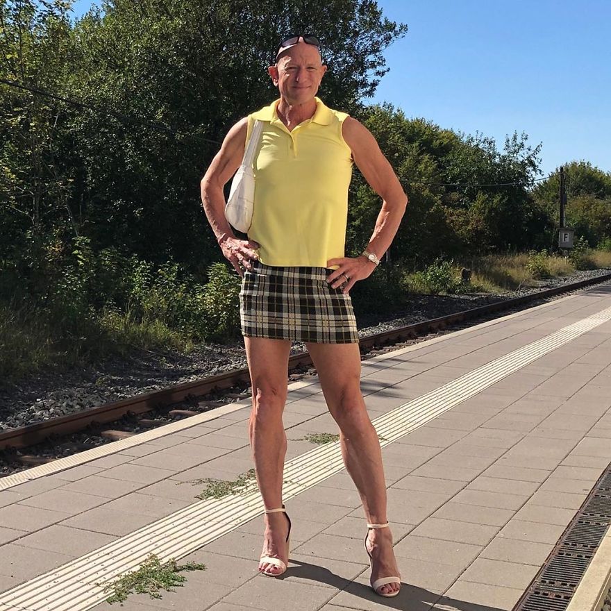 Mark Bryan is wearing a yellow sleeveless shirt, a plaid skirt, and open-high heels