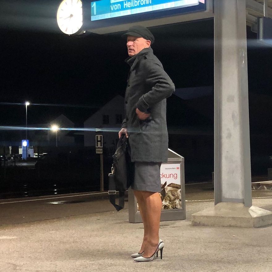 Mark Bryan in a gray outfit with a coat, skirt, newsboy hat, and white striped high heels