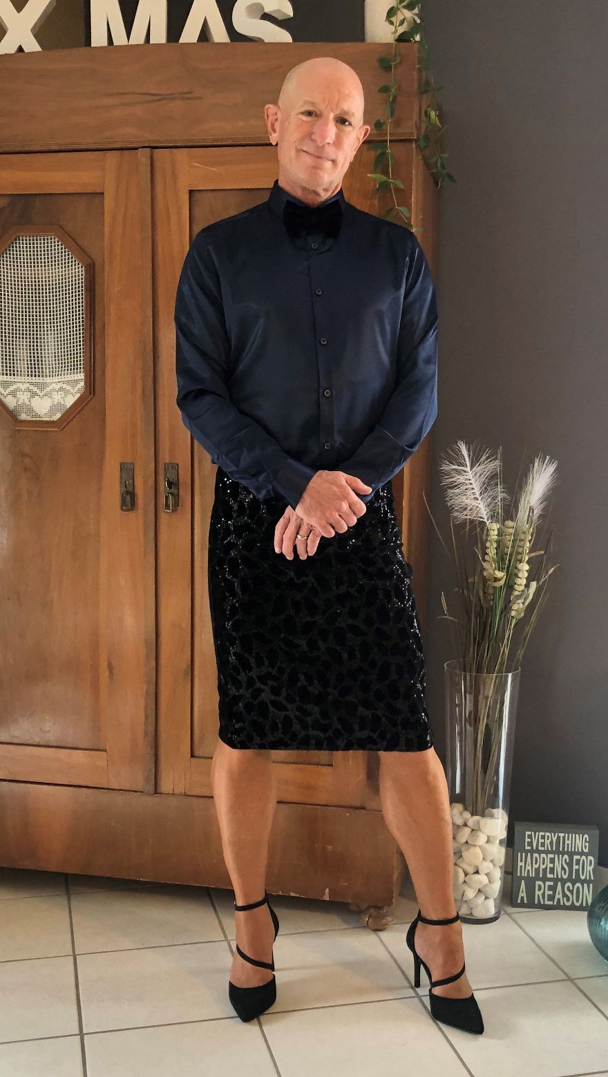 Mark Bryan in a dark outfit with a shirt, shiny skirt, and high heels