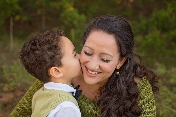 Young boy kissing his smiling mother outdoors, representing what every parent should tell their children about love and care.