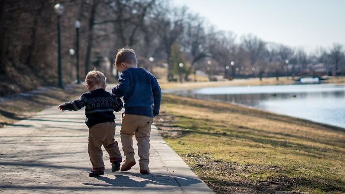 Two young children walking near a lake in a park, illustrating parent advice for children and family guidance.