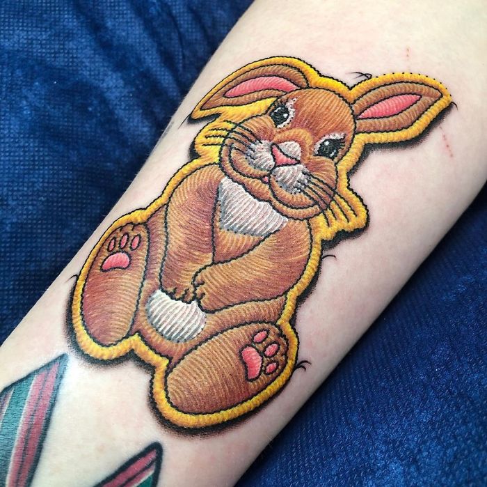 Sewn-on patch tattoo of a cute bunny on an arm, showcasing intricate artistic detail.