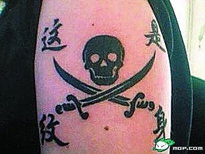 Tattoo with a skull and crossed swords, featuring foreign language text on a person's arm.